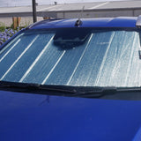 Blue car with a sunshade covering the windshield, parked outdoors.