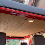 Wooden ceiling panel in a vehicle with headrests and a window in the background