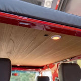 Wooden ceiling panel in a vehicle with headrests and a window in the background