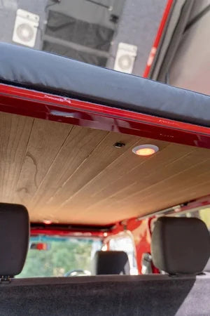 Wooden ceiling panel in a vehicle with headrests and a window in the background