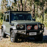 Green off-road vehicle with 'TORQIT' license plate in a forest setting
