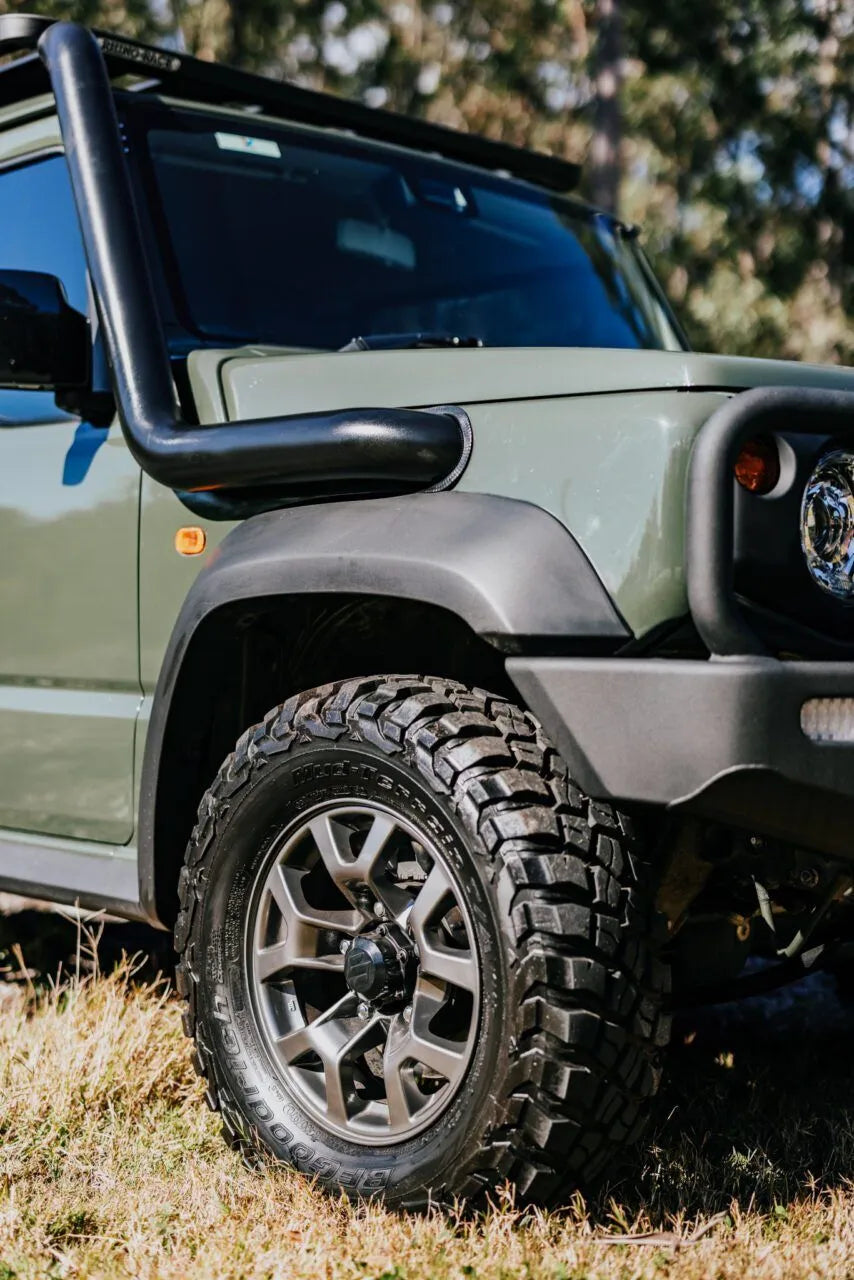 Green off-road vehicle with large tire and black bumper on grassy terrain