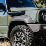 Green off-road vehicle with large tire and black bumper on grassy terrain