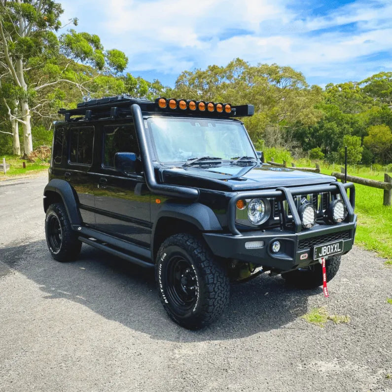 Black off-road vehicle on a road with trees in the background