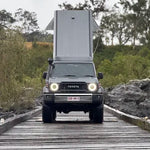 Toyota truck with a camper shell on a wooden bridge in a natural setting