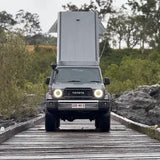 Toyota truck with a camper shell on a wooden bridge in a natural setting
