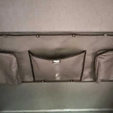 Gray storage compartment with multiple pockets on a vehicle interior.
