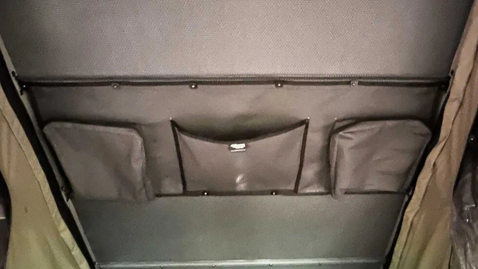 Gray storage compartment with multiple pockets on a vehicle interior.