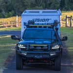 Black Toyota SUV with a Vision camper shell parked on a dirt road.