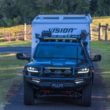 Black Toyota SUV with a Vision camper shell parked on a dirt road.
