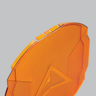 Close-up across the corner of an amber panoramic cover, showing the depth of the vertical ribbing, the stepped edge that locates on the lamp and the arrow moulded into the face