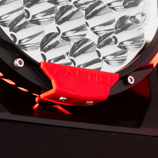 Close-up of the red ALTIQ trim tab clipped to the base of a Rogue light, with the chrome reflector cups above it and the mounting foot below