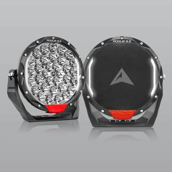 A pair of ALTIQ Rogue 8.5 driving lights side by side, one showing the reflector face with its dense cluster of LEDs and the ROGUE 8.5 marking on the bezel, the other fitted with a black cover carrying the ALTIQ arrow, both with red trim tabs at the base