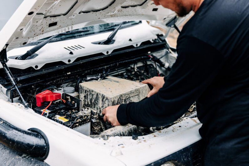 Person working on a car engine with a focus on the airbox area.