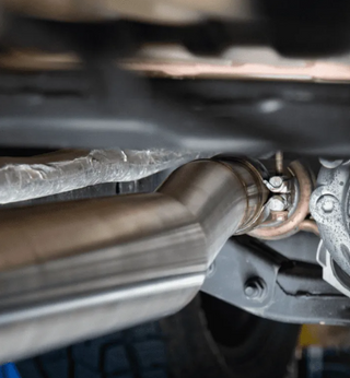 Close-up of a car exhaust system with a focus on the pipe and mounting hardware.