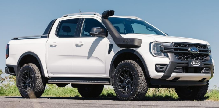 White Ford Ranger pickup truck on a road with a clear blue sky