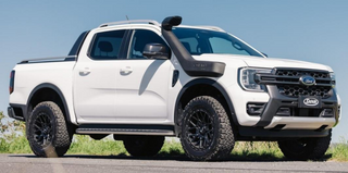 White Ford Ranger pickup truck on a road with a clear blue sky