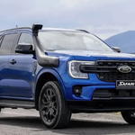 Blue Ford Safari SUV on a road with mountains in the background