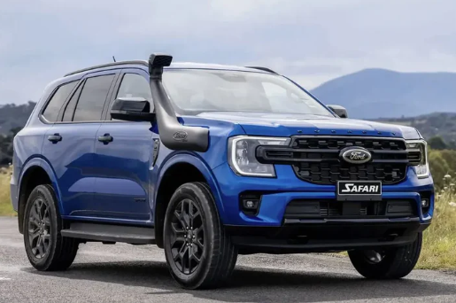 Blue Ford Safari SUV on a road with mountains in the background