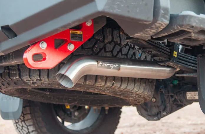 Close-up of a vehicle's exhaust system with a red component and 'Torqit' branding.