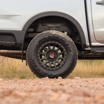 Close-up of a white truck with off-road tires on a dirt road