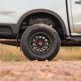 Close-up of a white truck with off-road tires on a dirt road