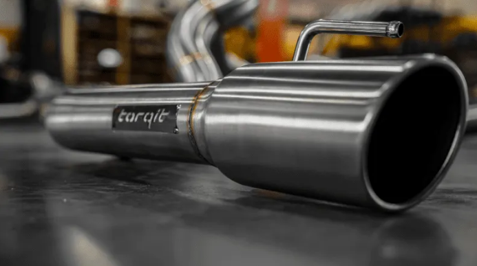 Stainless steel exhaust pipe with 'torqit' branding on a blurred background