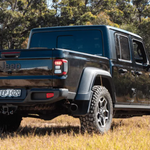 Black Jeep truck in a natural setting with trees and grass.