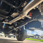 Close-up of a vehicle's undercarriage with visible suspension components on a road.