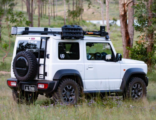 White SUV with roof rack and spare tire in a natural setting