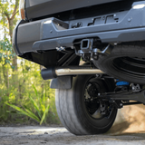 Close-up of a vehicle's undercarriage with a forest background