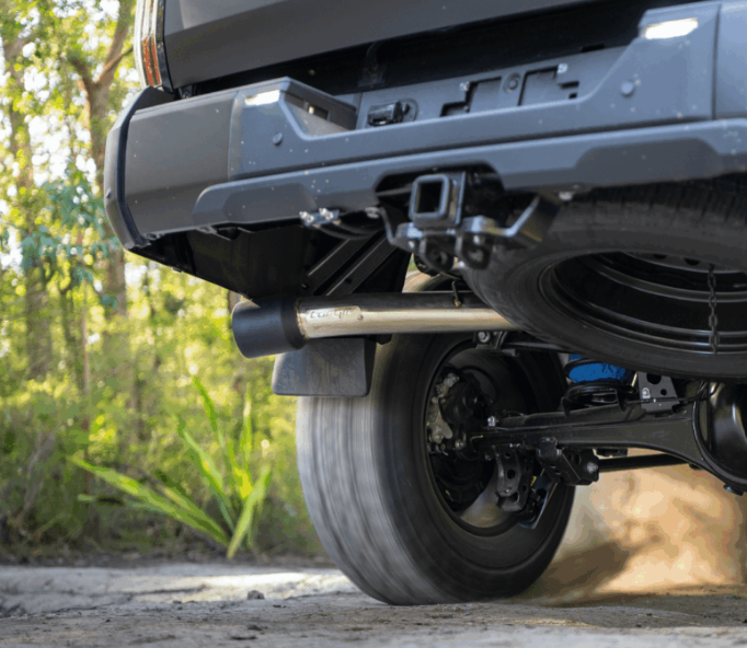 Close-up of a vehicle's undercarriage with a forest background