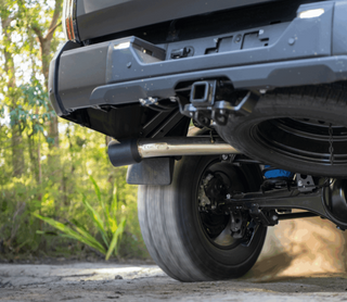Close-up of a vehicle's undercarriage with a forest background