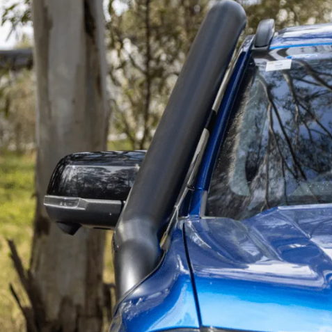 Close-up of a blue vehicle's side mirror and snorkel with trees in the background