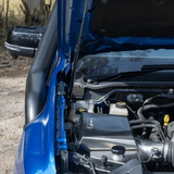 Close-up of a blue vehicle's engine compartment with visible components.