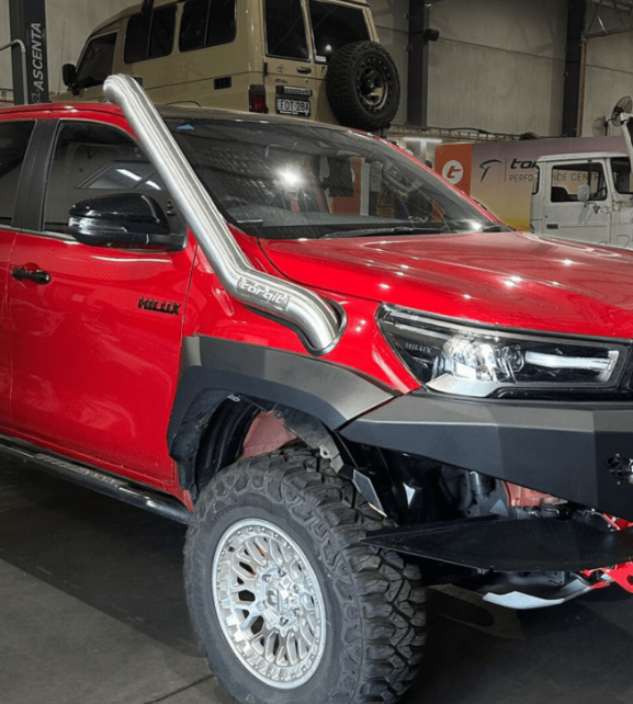 Red truck with off-road accessories in a showroom setting