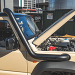Beige off-road vehicle with a black roll bar in an outdoor setting