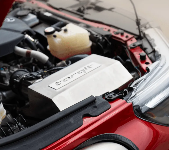 Car engine with a visible 'torqit' logo on a red car.
