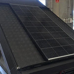 Solar panel on the roof of a vehicle with a building and car in the background