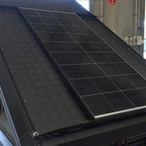 Solar panel on the roof of a vehicle with a building and car in the background