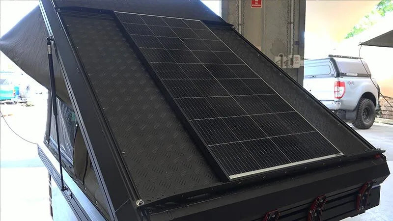 Solar panel on the roof of a vehicle with a building and car in the background