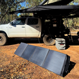 Solar panel on the ground next to a white truck in an outdoor setting