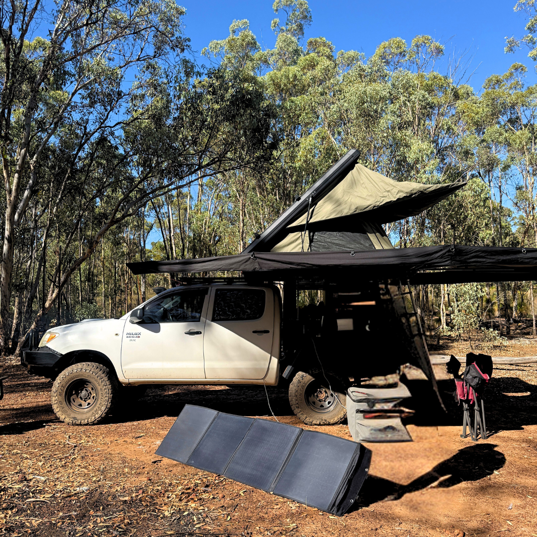 White truck with a large canopy in a forest setting