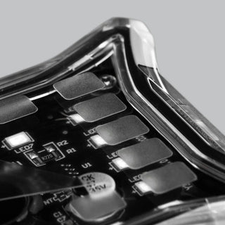 Close-up across the corner of a rock light, the clear lens curving away over the LED board with individual LEDs and the 47 microfarad capacitor in focus