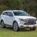 Silver Isuzu SUV parked on grass with trees in the background
