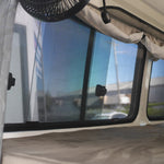 Close-up of an RV window with a fan and curtains