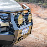 Close-up of a vehicle's front bumper with LED lights and a blurred natural background