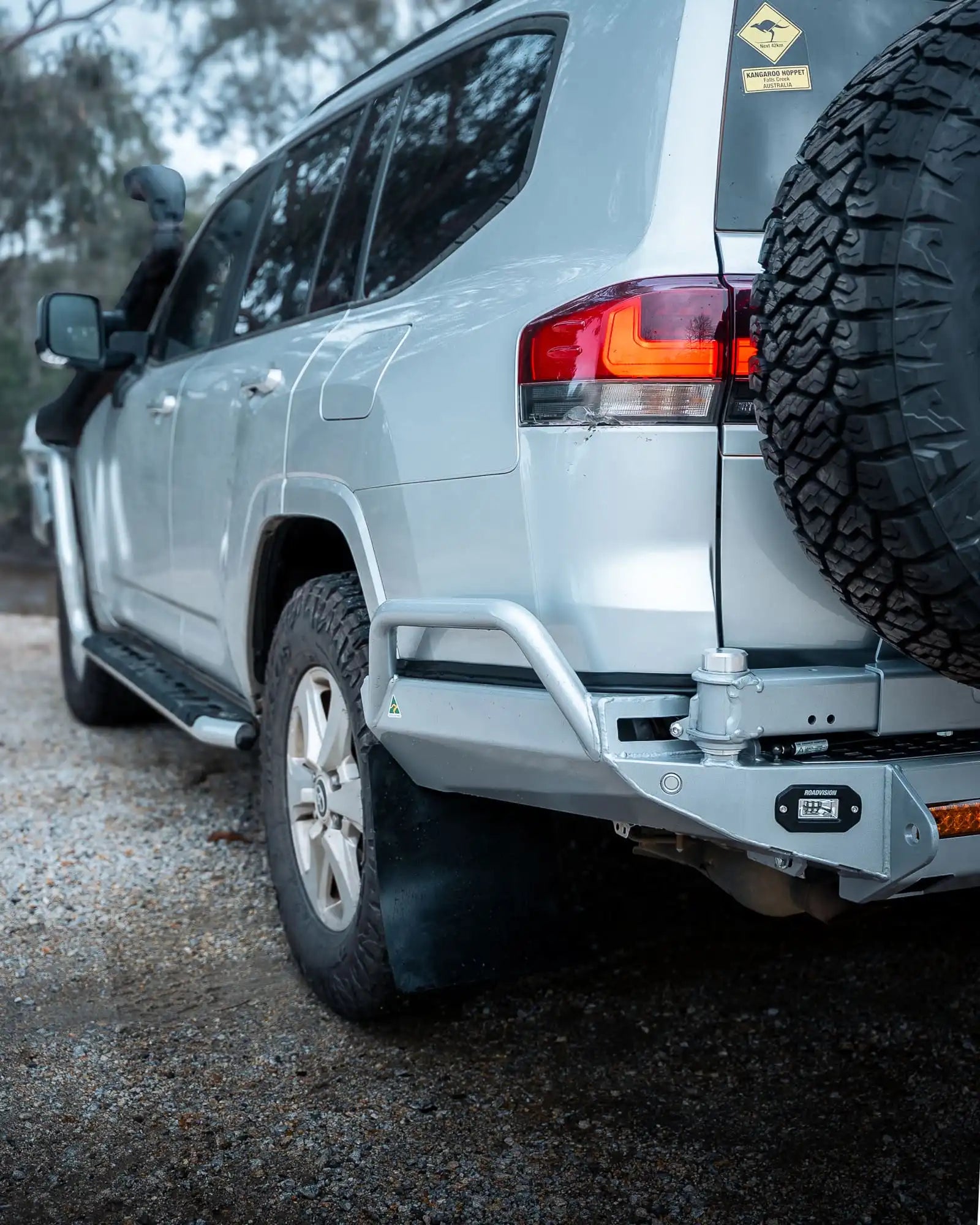 Silver SUV with off-road tire and bumper on a gravel surface
