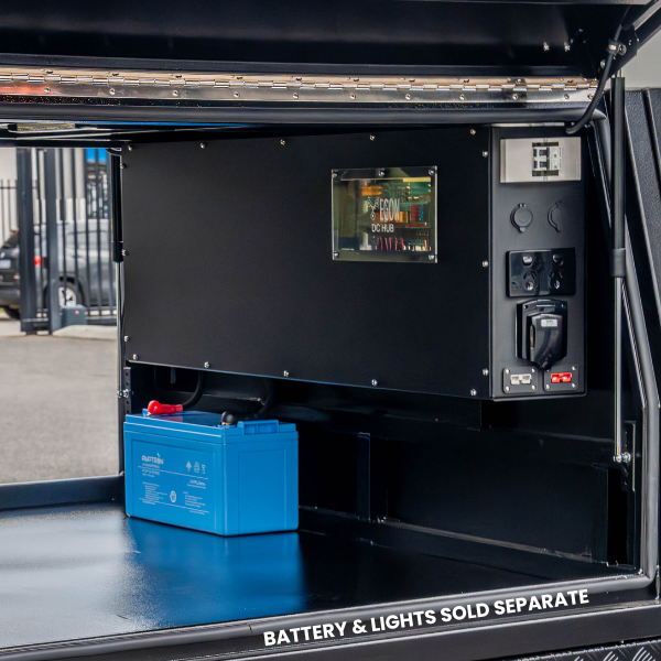 The Prospector canopy power system installed in a ute canopy, showing the EGON DC Hub viewing window, 240V outlets and 12V sockets on the end face, with a battery on the canopy floor