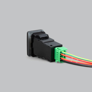 Black Toyota-fit switch seen from behind, the moulded body with a green connector carrying green, red, red and black wires running away to the right